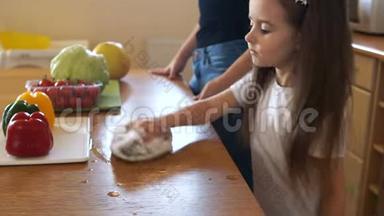 长发学龄前女孩用毛巾<strong>擦桌子</strong>。 妈妈和厨房里的小女孩。 妈妈`助理。 教育